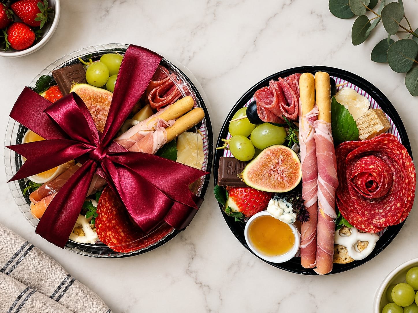 Dos tablas de Picando Tabla con quesos, jamón serrano, salami, higos, uvas, fresas y miel; una lista para regalo con moño